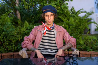 Portrait of young man wearing hat against trees