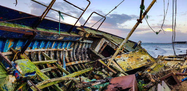 Abandoned boat on beach against sky