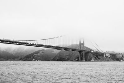 Suspension bridge over river against sky