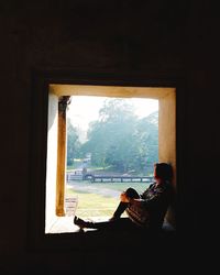 Side view of man sitting at window