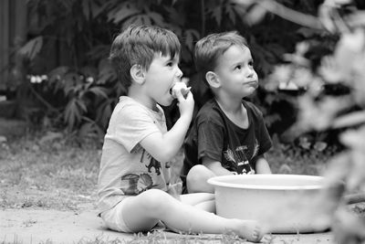 Brothers eating food while sitting on land