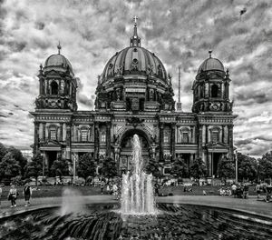 Water fountain in city against sky