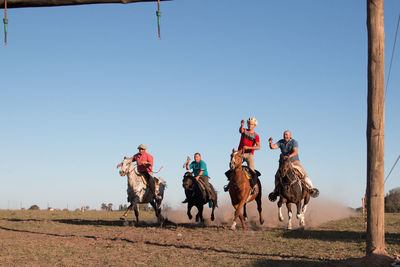 Group of people riding horses in field