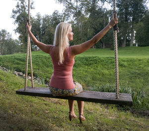 Rear view of young woman swinging at park