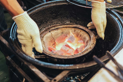 Close-up of person preparing food on barbecue grill