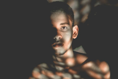 Close-up portrait of young man against black background