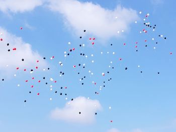 Low angle view of balloons flying against blue sky