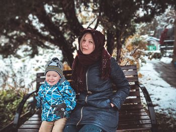 Portrait of happy woman standing against trees during winter