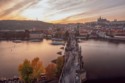 River amidst buildings in city against sky during sunset