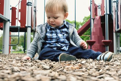 Baby boy playing with wood chips at playground