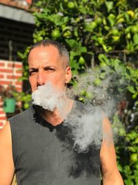 Portrait of man smoking against plants