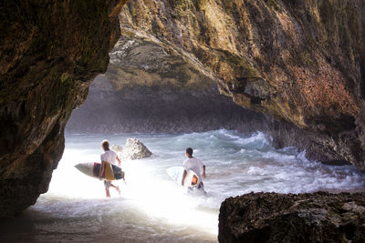 Men with surfboards in cave at beach