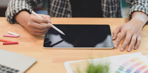 Midsection of man using smart phone on table