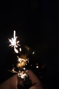 Close-up of hand holding lit candle in the dark