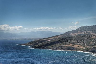 Scenic view of sea and mountains against blue sky