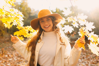 Young woman wearing hat standing against tree