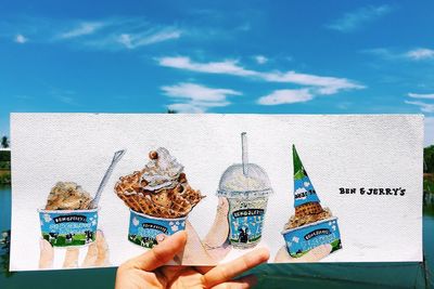 Man holding ice cream at beach against blue sky