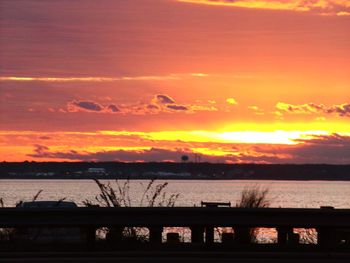 Silhouette bridge over river against orange sky