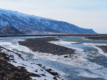 Scenic view of frozen sea by mountains against sky