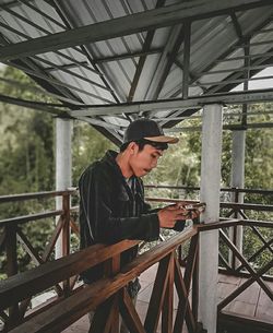 Side view of man using mobile phone by railing