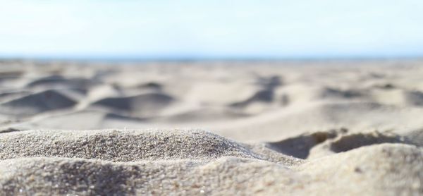 Close-up of pebbles on sand at beach against sky