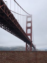 Low angle view of suspension bridge against sky