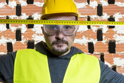 Portrait of confident architect with tape measure at construction site