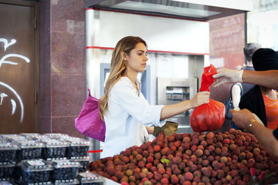 Woman buying fruits at market stall