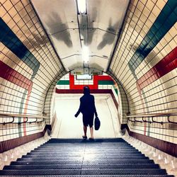 Rear view of woman walking in tunnel
