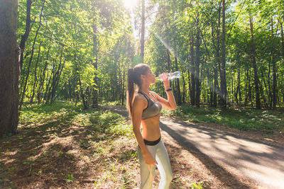 Woman standing by tree in forest