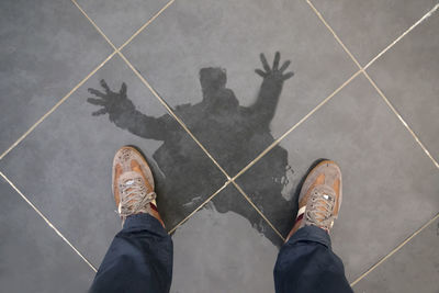 Low section of man standing on wet tiled floor