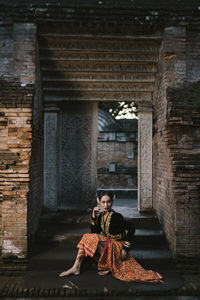Woman in traditional clothing looking away while sitting in historic building