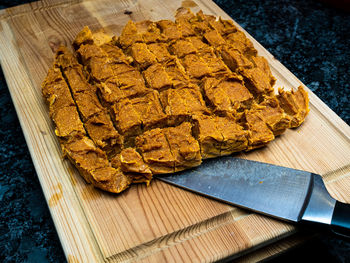 Home made dog treats made of pumpkin on a wooden cutting block with a knife.
