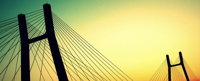 Low angle view of suspension bridge against sky during sunset