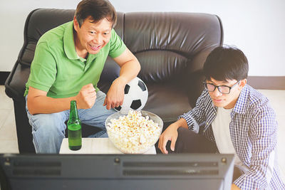 Excited father and son watching tv at home