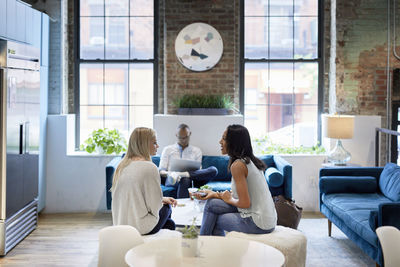 Businesswomen communicating while male colleague working on laptop at office