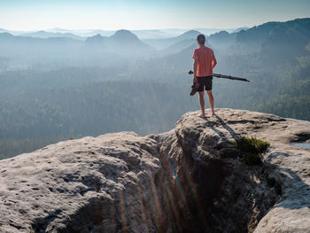 Photographer holds tripod with camera  and rejoices in beautiful day. nature lover and photographer