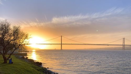 View of suspension bridge over sea during sunset