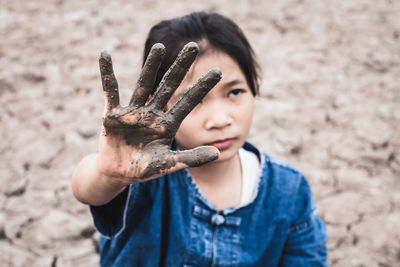 Girl with muddy hand on drought field