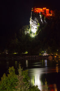 View of illuminated bridge over river at night
