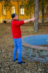 Full length of man standing by tree trunk