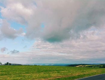 Scenic view of grassy field against cloudy sky