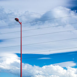 Low angle view of street light and power cables against cloudy sky