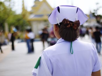 Rear view of woman wearing uniform standing in city