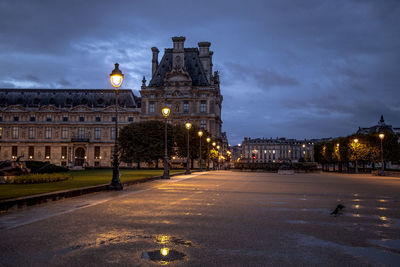 Illuminated city street against sky at night