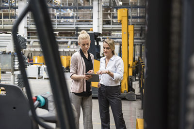 Two women with tablet talking in factory shop floor