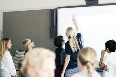 Teacher explaining students on whiteboard in classroom