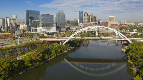 Bridge over lake by buildings in city against sky