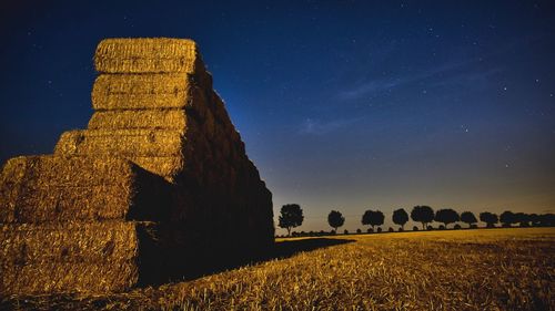 Hay bales on farm against blue sky at dusk