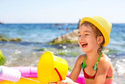 Smiling girl with toys at beach